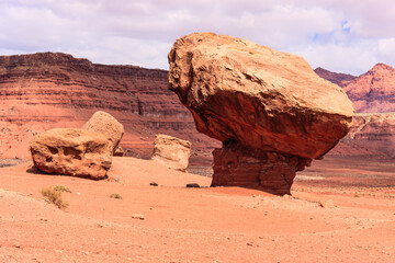 A large rock sits in the desert, surrounded by smaller rocks