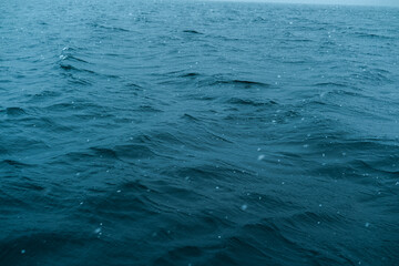 Fototapeta premium Waves ripple on a deep blue sea during a gentle rain shower