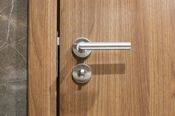 Wooden door with metal lock and handle. Shiny lock security detail. Rustic aged wood. Home and apartment entrance. Interior and exterior design. Safe and protective doorway. Bathroom door interior.