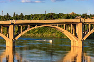 Fototapeta premium A bridge spans a river with a boat in the water
