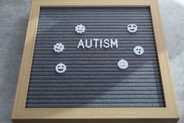 Autism with face tiles around the word. Sunlight across the board