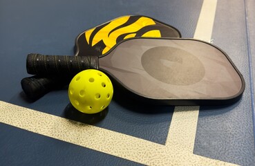 Fototapeta premium Pickleball tennis racket on the court. Blue background with copy space. Sport court and ball.