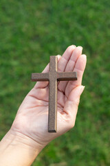 Wooden cross rests open palm, symbolizing faith, hope, devotion Christianity worship. Prayerful hands sacred cross, reflecting spirituality, trust, forgiveness divine belief.