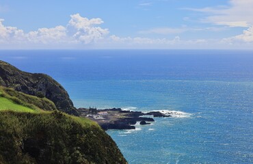 Coastal landscape with green cliffs and blue ocean.
