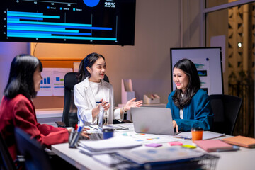 Three women are sitting at a table in a conference room, discussing a project