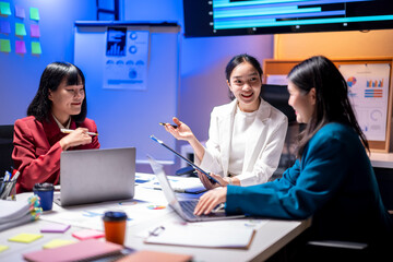 Three women are sitting at a table in a conference room, smiling