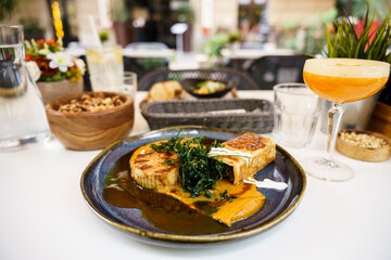 Gourmet plated dish with vibrant sauce and cocktail in restaurant setting