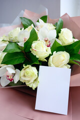Blank Greeting card paper note in bouquet of white roses and orchids in bottom packaging. Valentine's Day and love concept