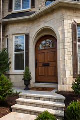 Elegant Stone House Entrance with Arched Wooden Door and Landscaping