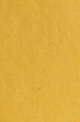 A close-up view of yellow paper with a textured surface. The paper has a subtle grainy texture with visible fibers, creating a rustic and aged look