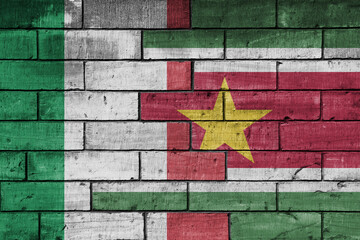 colourful painted big flag of italy and flag of suriname on a massive old brick wall background....