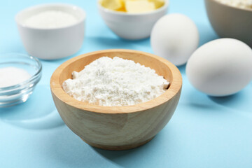 Baking powder and other ingredients for making dough on light blue background, closeup