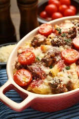 Delicious pasta casserole with cheese, tomatoes, minced meat and thyme in baking dish on table, closeup