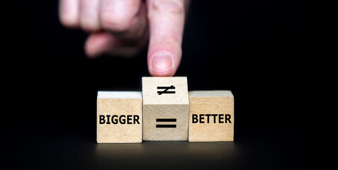 Hand turns cube and changes an equal sign to an unequal sign. Symbol that bigger is not necessarily...