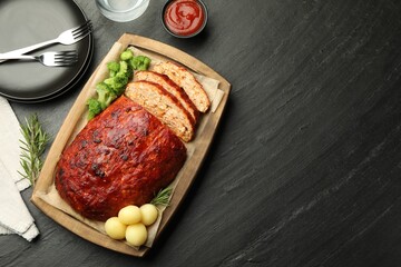 Delicious turkey meatloaf with vegetables served on black table, flat lay. Space for text