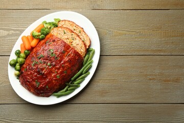 Delicious baked turkey meatloaf with vegetables on wooden table, top view. Space for text