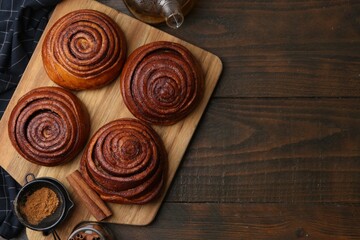 Delicious cinnamon rolls, sticks and powder on wooden table, flat lay. Space for text