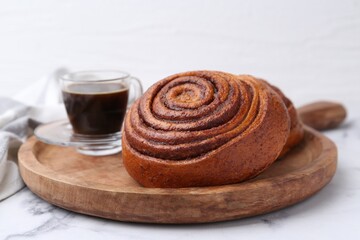 Delicious cinnamon roll and coffee on white marble table, closeup