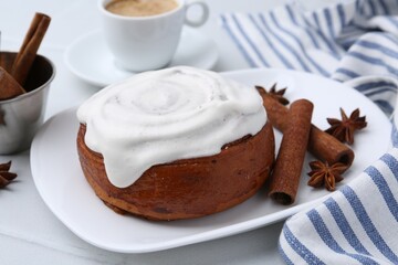 Tasty cinnamon roll with cream, spices and coffee on white tiled table, closeup