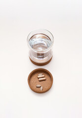 Vitamin capsules and glass of water. Medical still life.