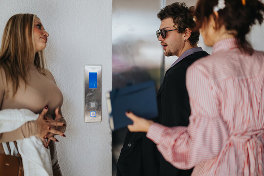Three business people engage in conversation near an elevator, showcasing a casual and comfortable workspace environment. Their interaction reflects modern workplace dynamics and communication in an