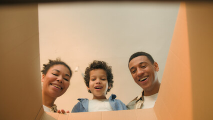 Point of view POV open box African american family parents son unpacking cardboard parcel happy...