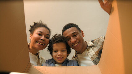 Point of view POV open box African american family parents son unpacking cardboard parcel happy...