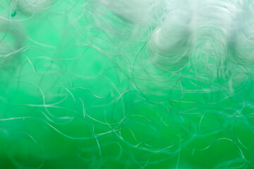 Extreme macro of polyester stable fiber on green background. Selective focus, shallow depth of field. Abstract dreamy background