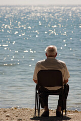 Fototapeta premium Elderly man gazing at tranquil water on a sunny day
