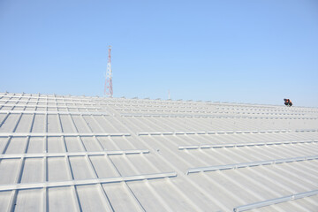 sloped metal roof. The roof has a series of parallel ridges and is equipped with numerous mounting brackets, likely for the installation of solar panels or another type of equipment