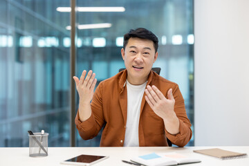 Webcam view, video call, Asian man looking at camera, smiling and communicating with colleagues and...