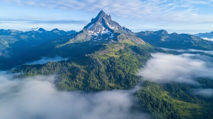 Aerial view of a mountain peak surrounded by mist and rugged alpine terrain