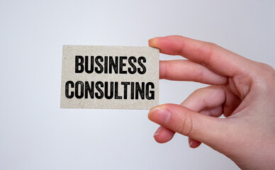 Business consulting message written on a card in hand. Conceptual business consulting symbol. Copy space.