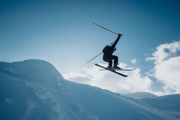 A skier skillfully executes a mid-air maneuver during an adventure in a snowy mountain setting.