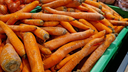 Washed ripe carrots on sale in the store. Carrots close-up. Vegetable crop. A pile of washed carrots in a plastic box, selective focus. Vegetables in the supermarket close-up