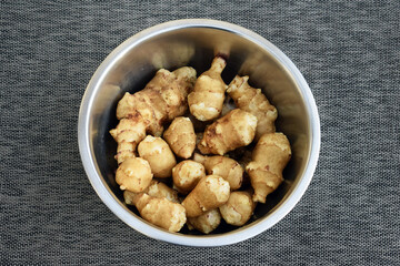 Jerusalem artichoke (Helianthus tuberosus) tubers, just harvested. Washed tubers in a bowl 