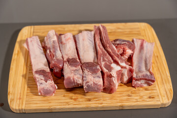 A slab of meat is cut into pieces and placed on a wooden cutting board. The meat is cut into strips and is ready to be cooked