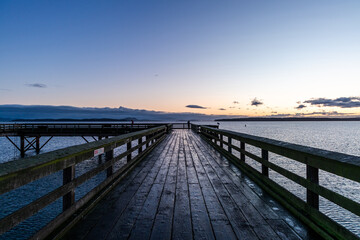 Naklejka premium Scenic Wooden Pier Extending Into the Ocean During Serene Sunset