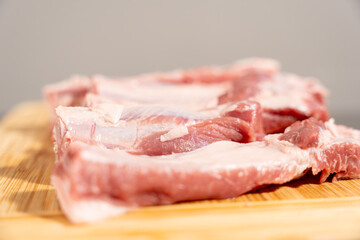 A piece of meat is on a wooden cutting board. The meat is cut into slices