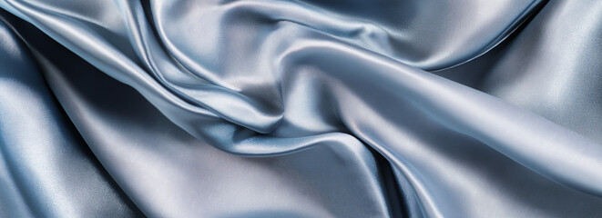 Obraz premium A close-up view of the surface texture of silver fabric, showcasing a smooth and slightly wavy appearance. The dark gray background enhances the details of the light blue material, bringing out its su