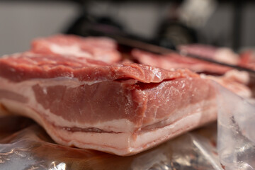 A piece of meat is on a table. It is cut in half. The meat is pink and has a white strip