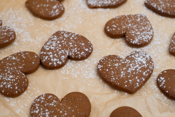 Gingerbread heart cookies on parchment paper. Delicious baking
