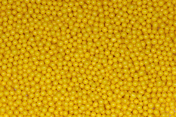 Vibrant Yellow Sugar Sprinkles Background: Macro Photography of Decorative Candy Pearls Used for Cake Decoration and Confectionery Garnish