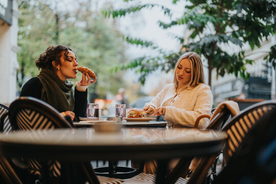 Two women are sharing a meal at an outdoor cafe, enjoying the relaxed atmosphere.