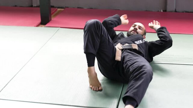 Martial arts athlete practicing forward rolls and breakfalls on tatami mats