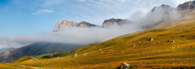 Russia. The Elbrus region. The high mountain peaks of the North Caucasus are surrounded by morning misty clouds hovering at different levels of inaccessible rocks.