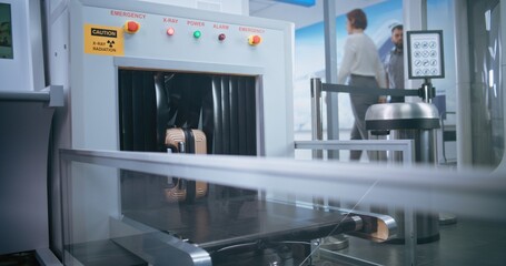 Security Checkpoint in Airport Terminal: Passenger Places Suitcase on Conveyor Belt for Luggage...