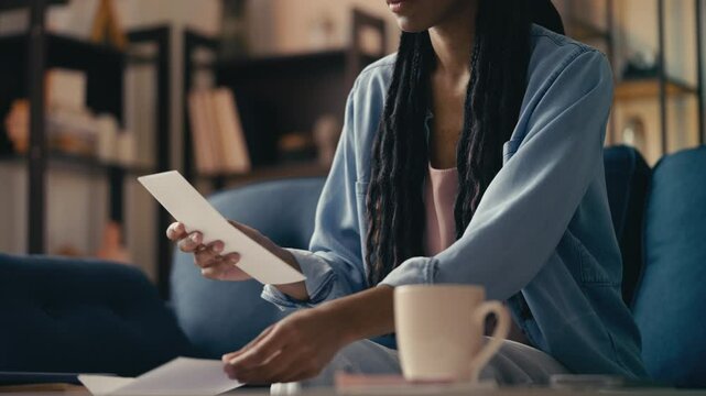 African American woman opens an envelope and reads a letter, feels disappointed
