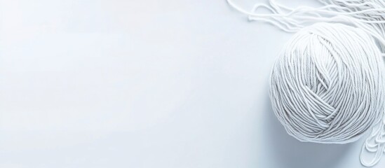 Obraz premium White yarn ball on white background, strands trailing, crafting concept