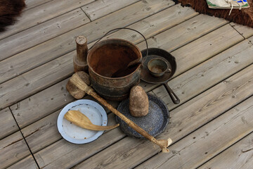 A wooden table with a pot, a pan, a spoon, and a plate